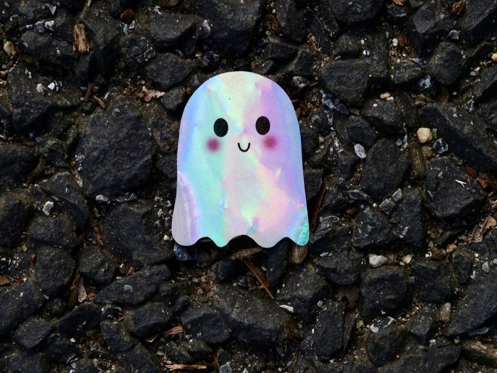 Holografinis vaivorykštinis lipdukas, priklijuotas ant tamsaus žvyro